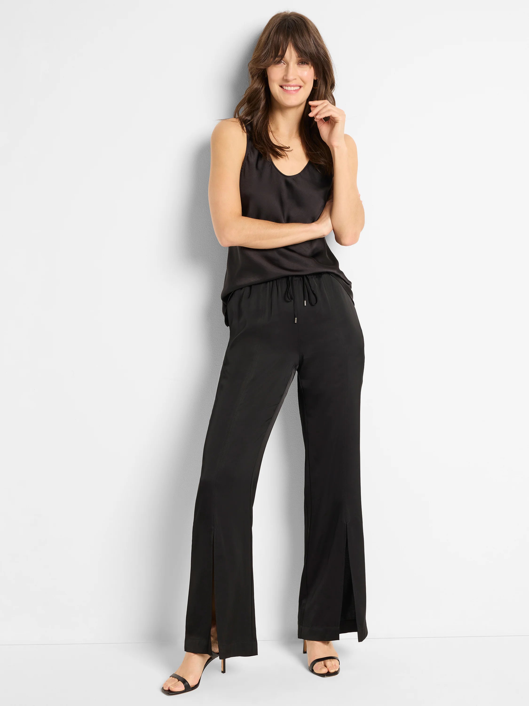 Black woven pants with side slits and drawstring waist. Model is wearing a matching black top.