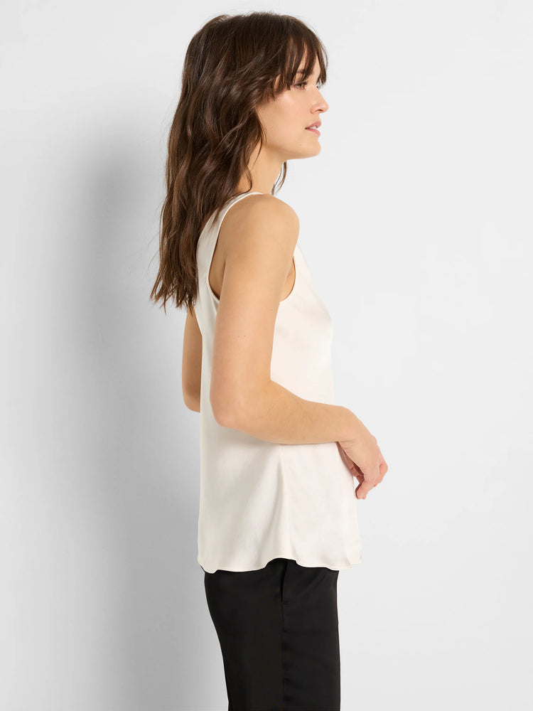 Off-white sleeveless scoop-neck satin top. A-line shape. Model shown wearing black pants.