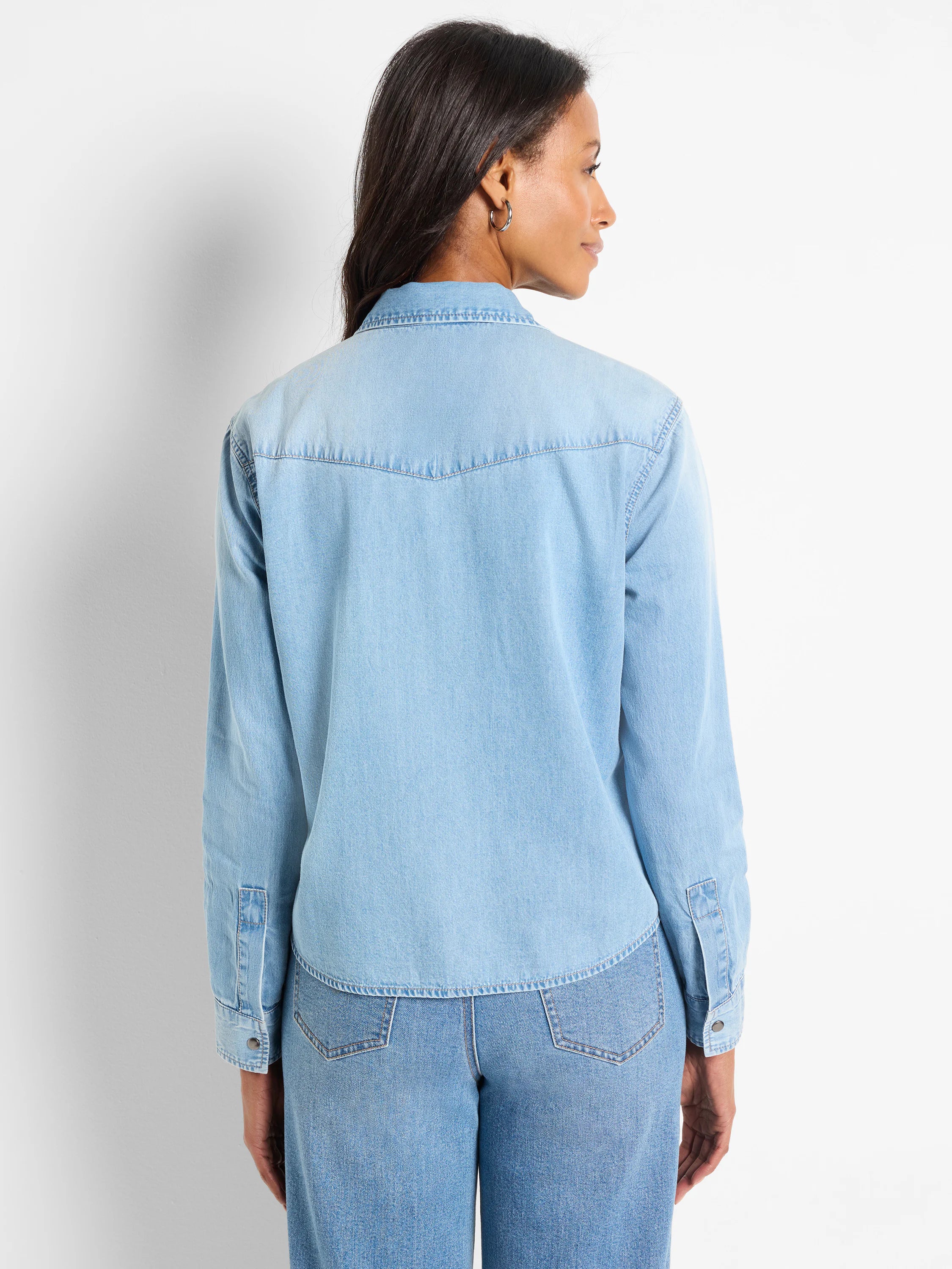 Light blue denim shirt, long sleeves, button front, yoke detail on back. Shown on a model.