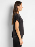 Black, short-sleeved woven top; slightly curved hemline.  Side profile shown.
