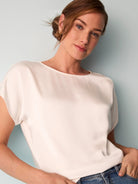 Off-white woven top with short sleeves and a round neckline.