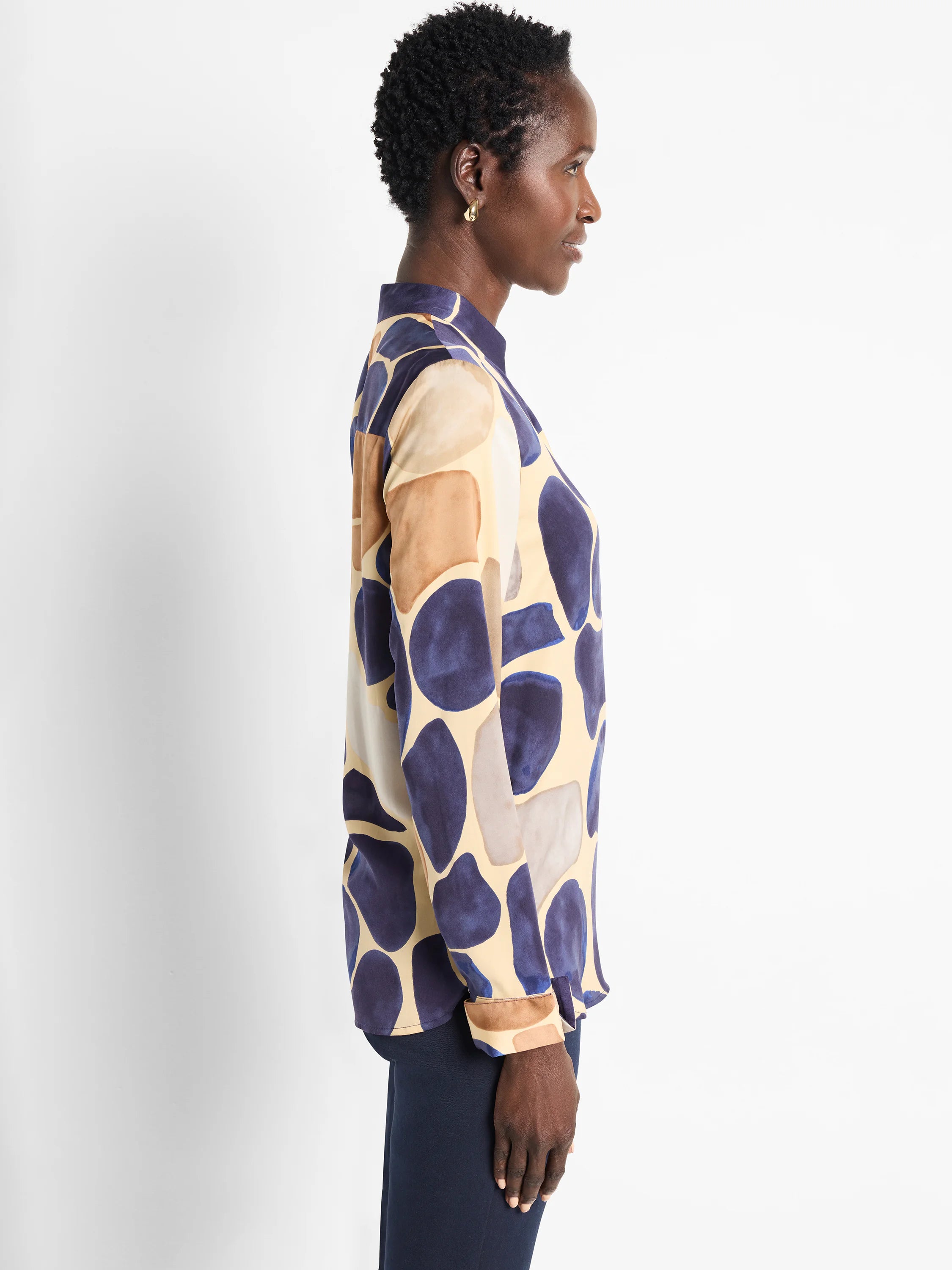 Long-sleeve woven shirt. Beige background with abstract blue, brown, and gray pebble pattern. High neckline.