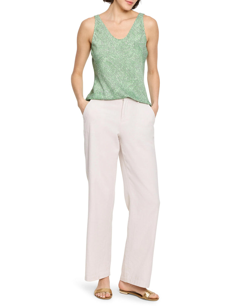 Green sleeveless tank top with a subtle swirling pattern. V-neck. Model also wears off-white pants and gold sandals.