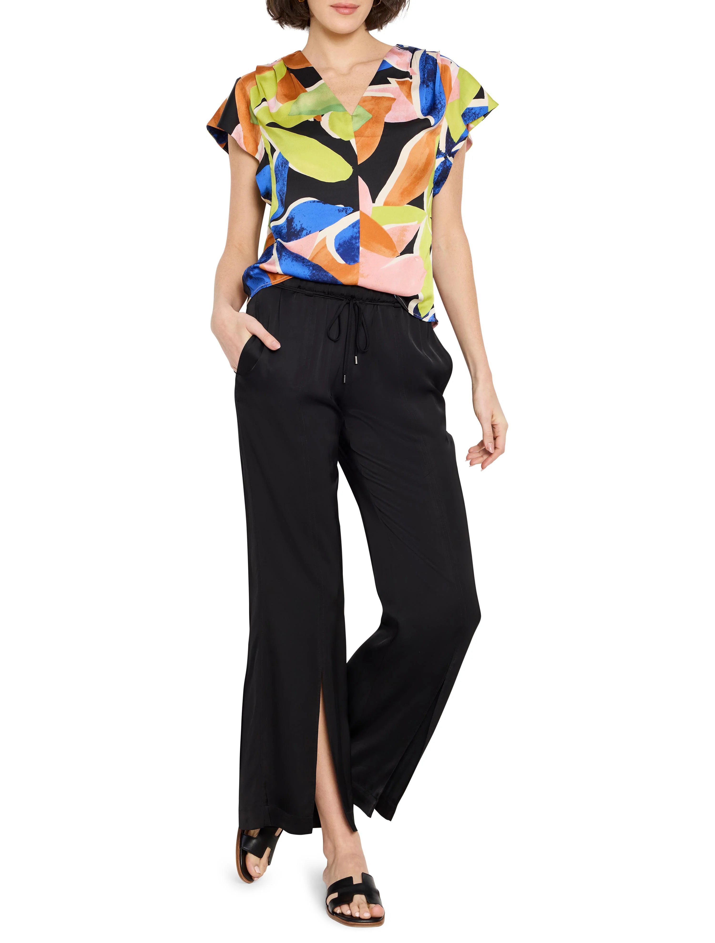 Woman wearing short-sleeved V-neck top with abstract blue, orange, pink, & lime green print on black background; paired...