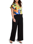 Short-sleeved V-neck top with lime, orange, pink, blue abstract leaf print on black background.  Paired with black...