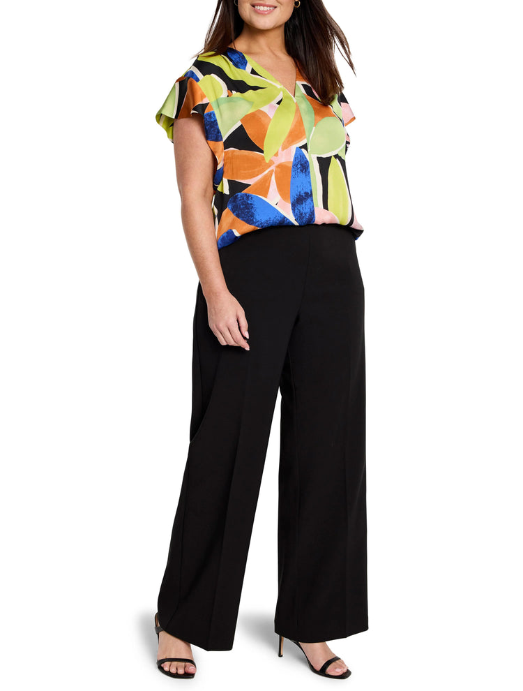 Short-sleeved V-neck top with lime, orange, pink, blue abstract leaf print on black background. Paired with black...