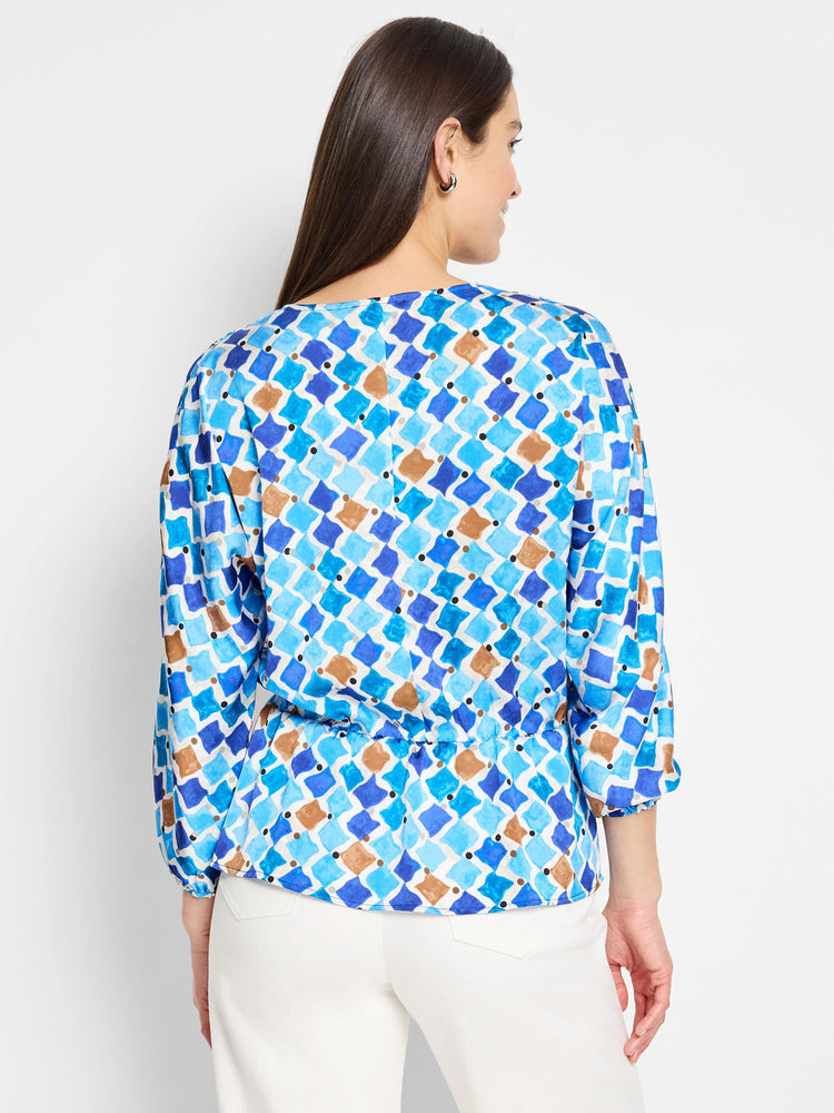 White top with blue, brown, and black mosaic-style diamond pattern. Three-quarter sleeves, fitted waist.