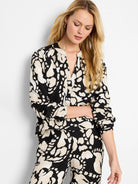Black woven shirt with beige abstract print, long sleeves, and a V-neck.