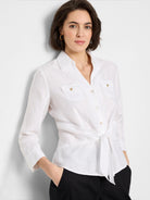 White linen shirt with three-quarter sleeves, button front, tie waist, and two chest pockets; gold buttons.