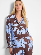 Brown and light blue floral print woven top with long sleeves and button front.