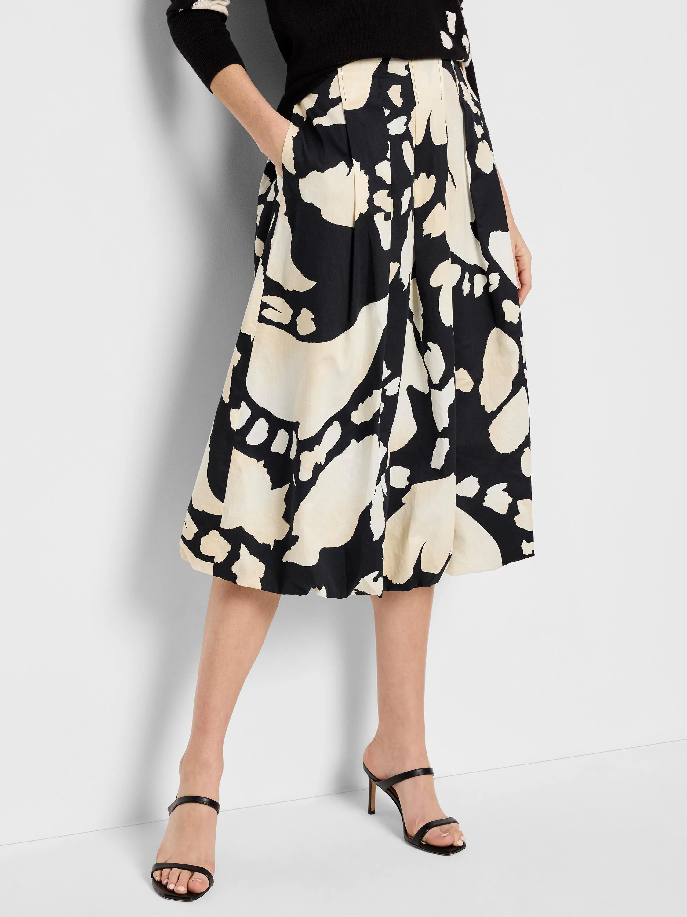 Black pleated midi skirt with an abstract beige and black print.  Features pockets.