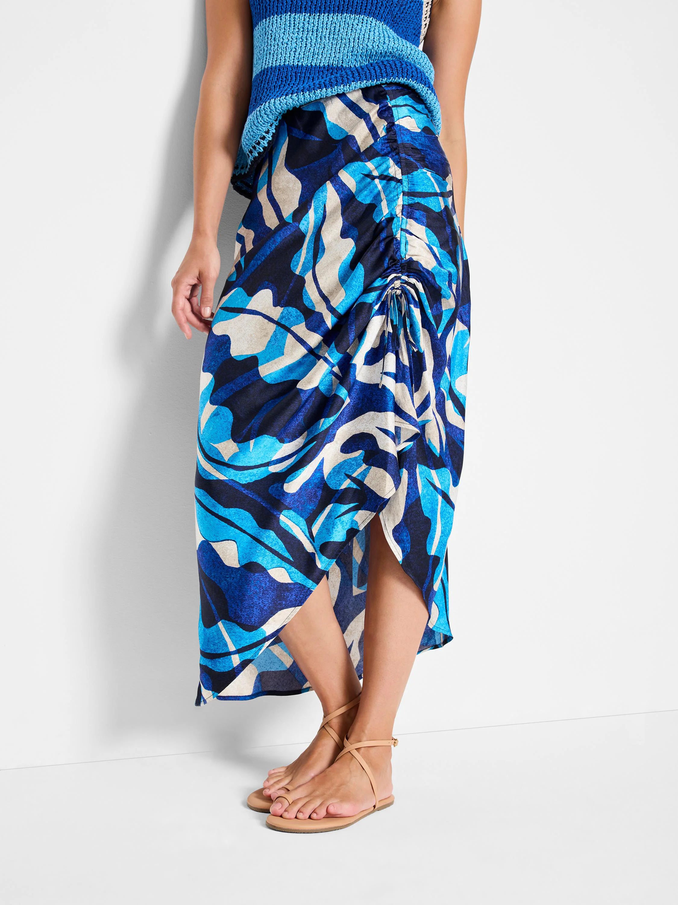 Blue, teal, and off-white abstract print midi skirt with a ruched side and asymmetrical hem.