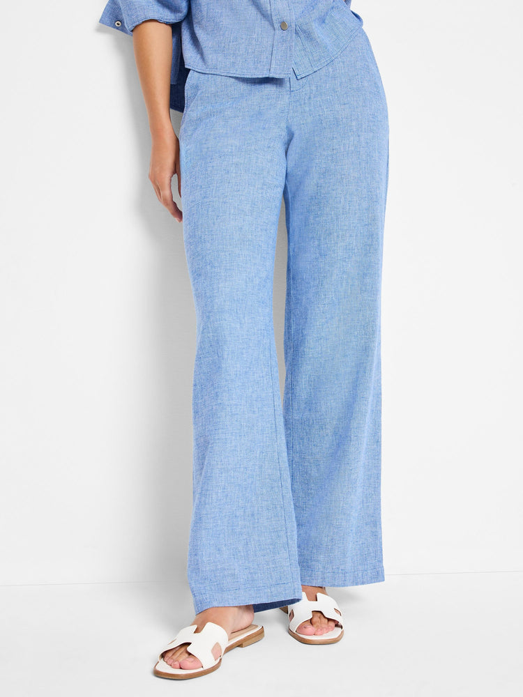 Light blue linen-cotton wide-leg pants. The pants are shown on a model, with a textured fabric.
