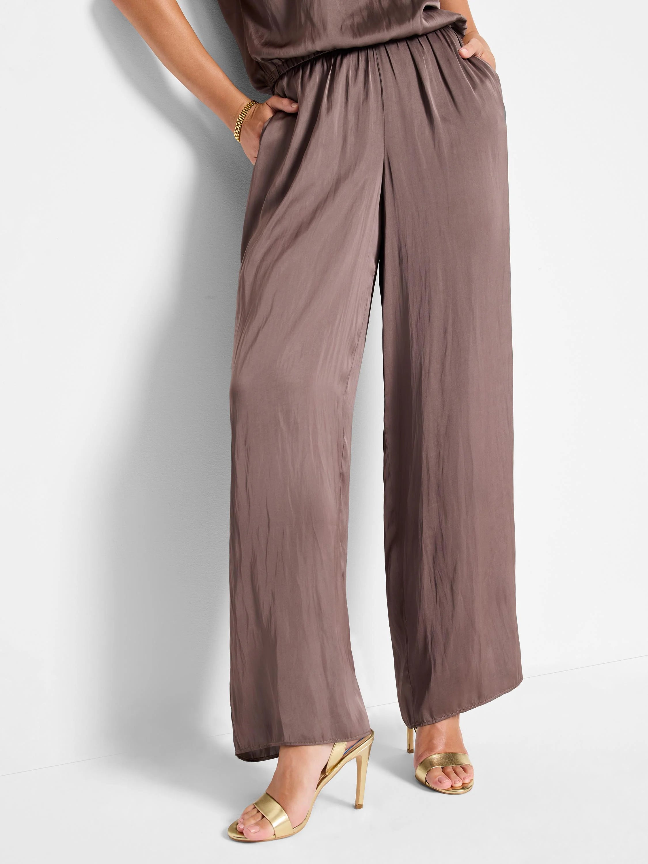 Mauve wide-leg pants with a pull-on waistband.  Glossy sheen fabric. Model wears gold heels.