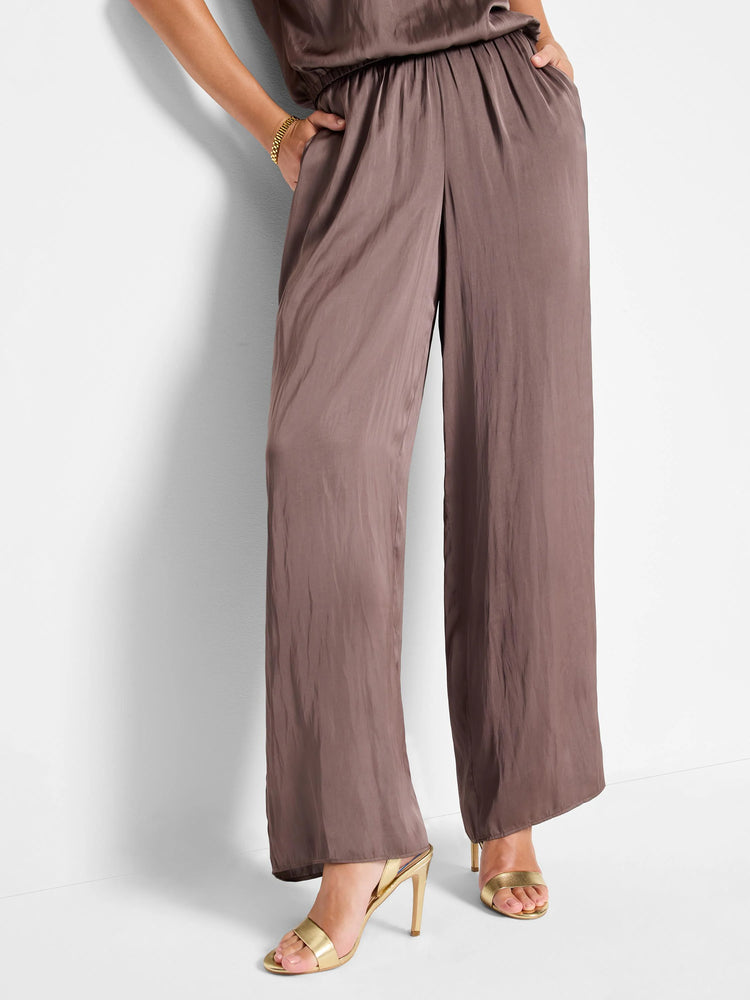 Mauve wide-leg pants with a pull-on waistband. Glossy sheen fabric. Model wears gold heels.