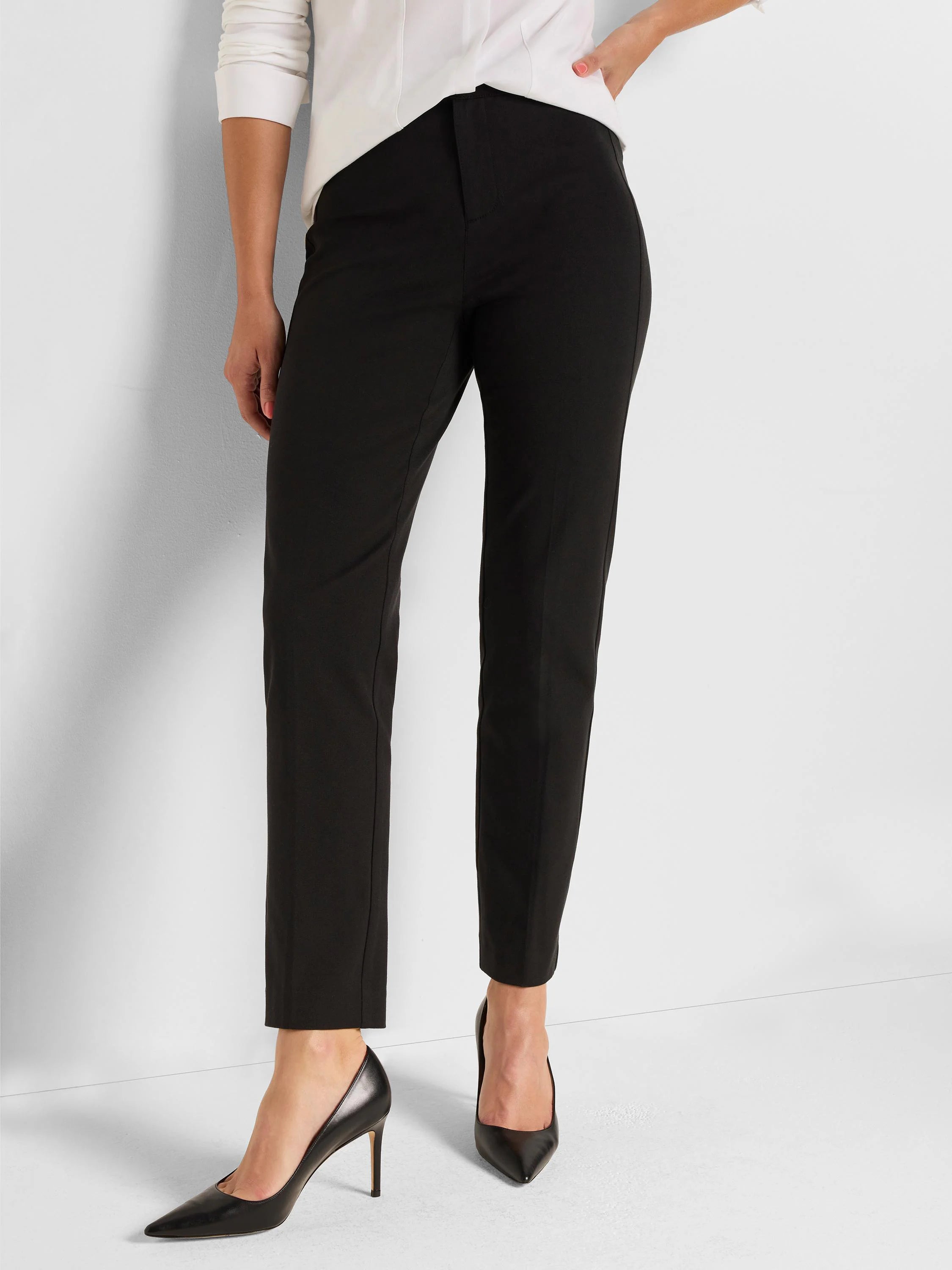 Black straight-leg pants on a model. They feature a flat front and subtle creases, ending at the ankle.