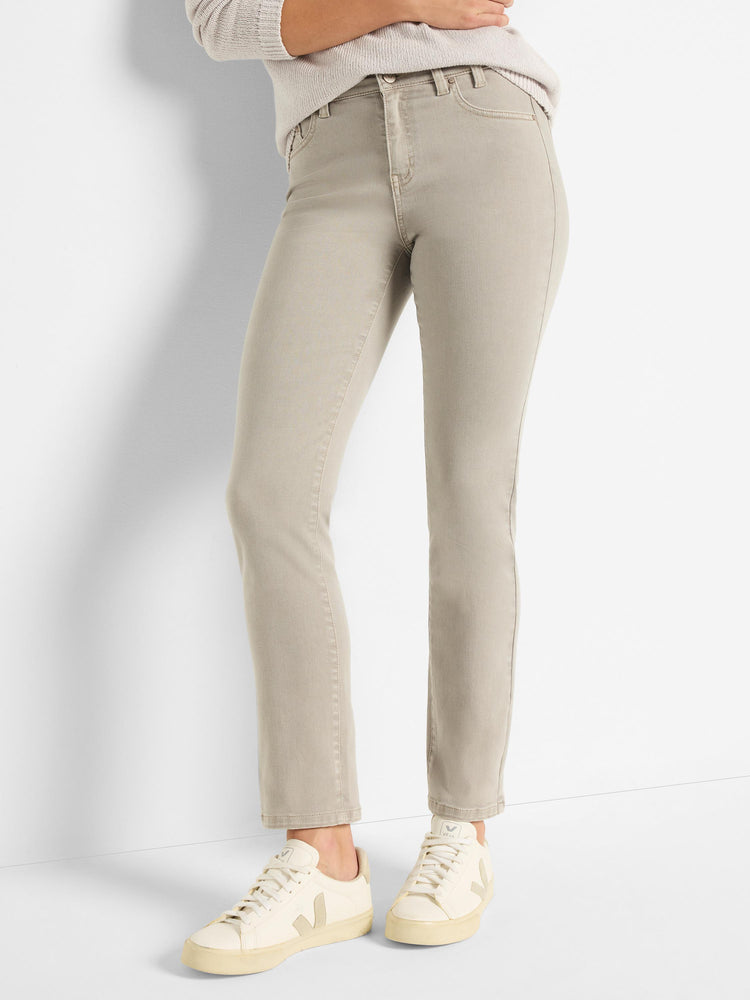 Model wears slim-fit, straight-leg jeans in a light taupe color with classic five-pocket styling.
