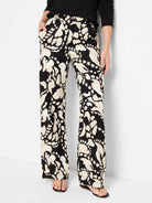 Black wide-leg pants with a beige abstract print.  The print features irregular shapes and patterns.