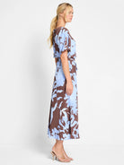 Brown midi dress with light blue abstract floral print, short sleeves, and a self-tie belt.