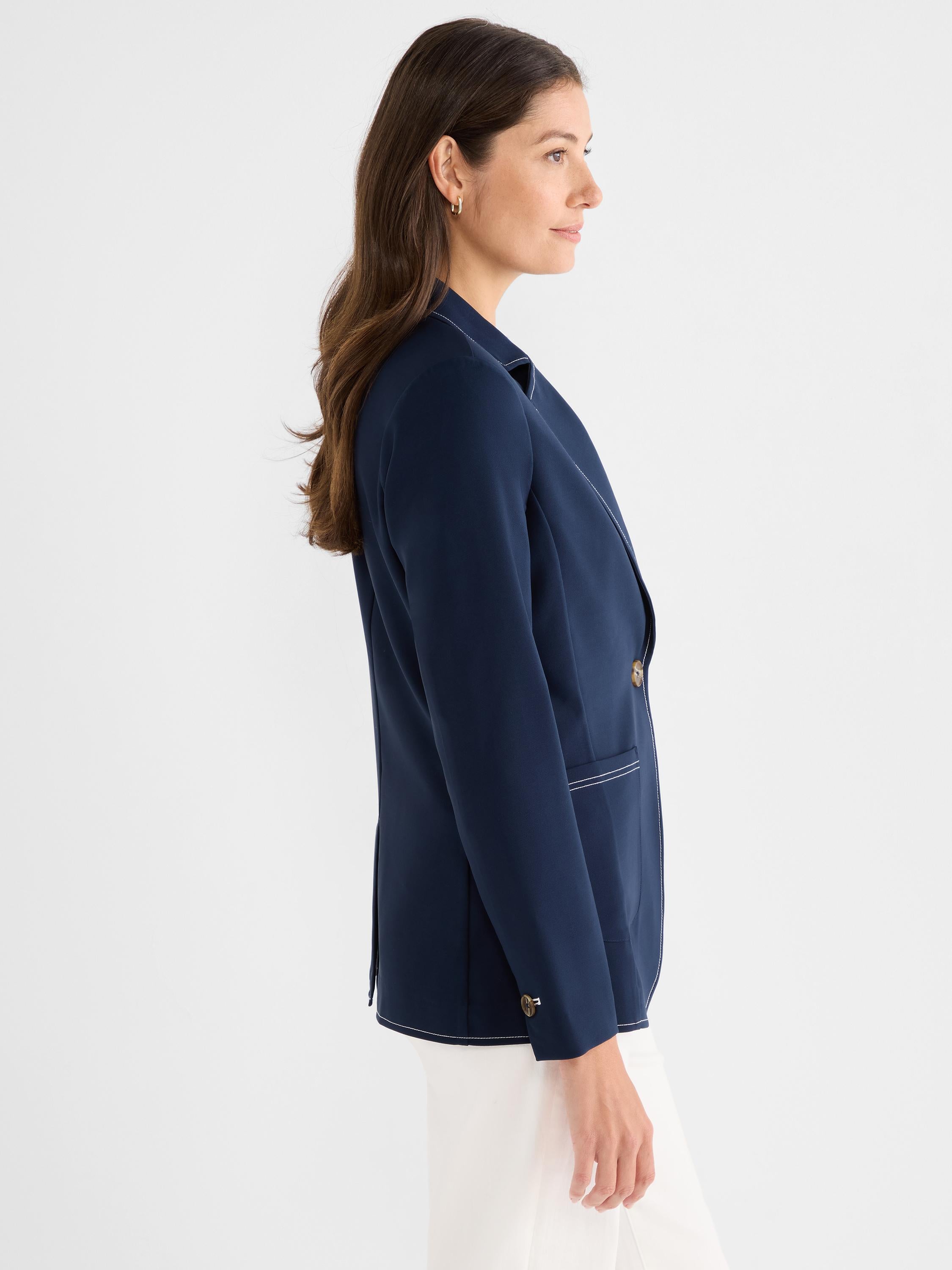 Structured navy blazer features white contrast stitching detailing the lapels, pockets, and hem.