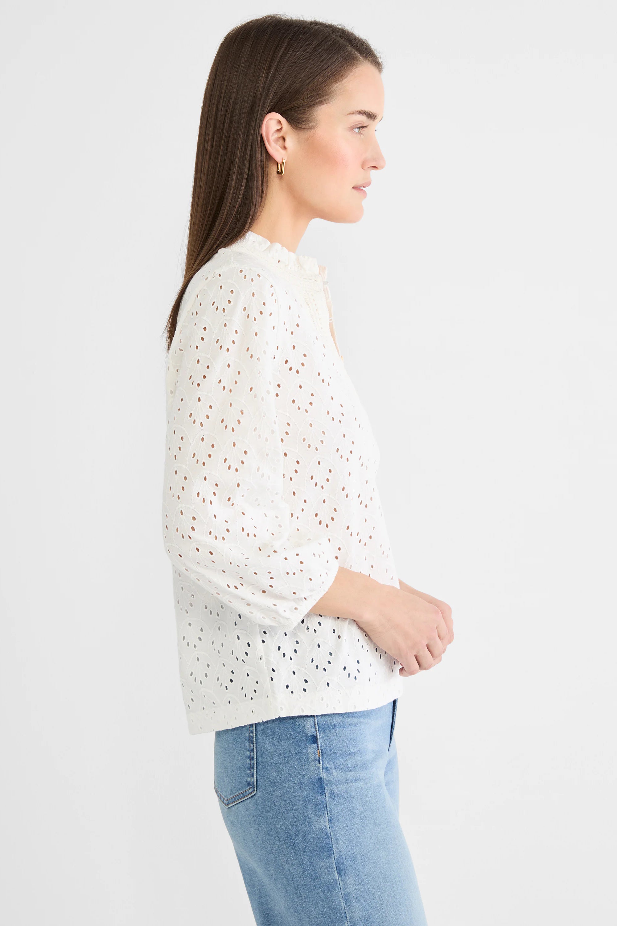 White knit top with leaf-patterned eyelets, ruffled neck, and 3/4 puff sleeves, worn on model.