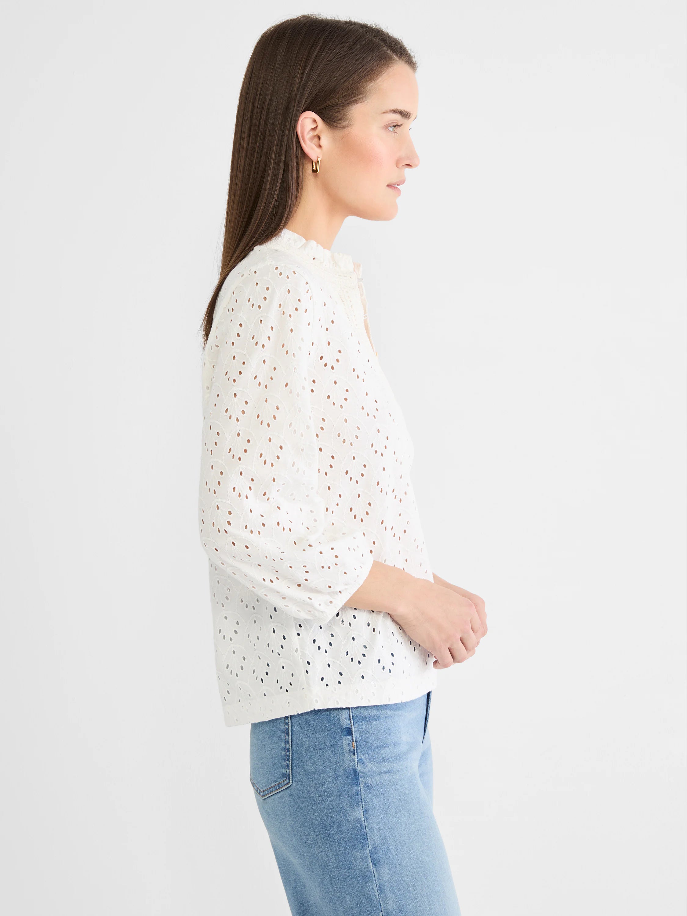 White knit top with leaf-patterned eyelets, ruffled neck, and 3/4 puff sleeves, worn on model.