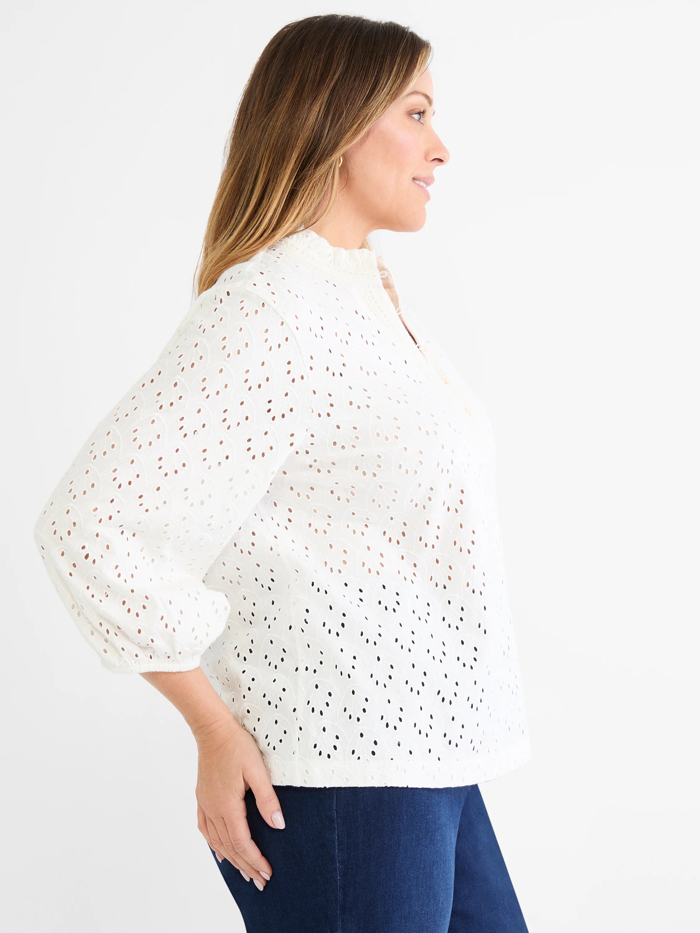 White knit top with leaf-pattern eyelets, a ruffled mock neck, and gathered 3/4 sleeves.