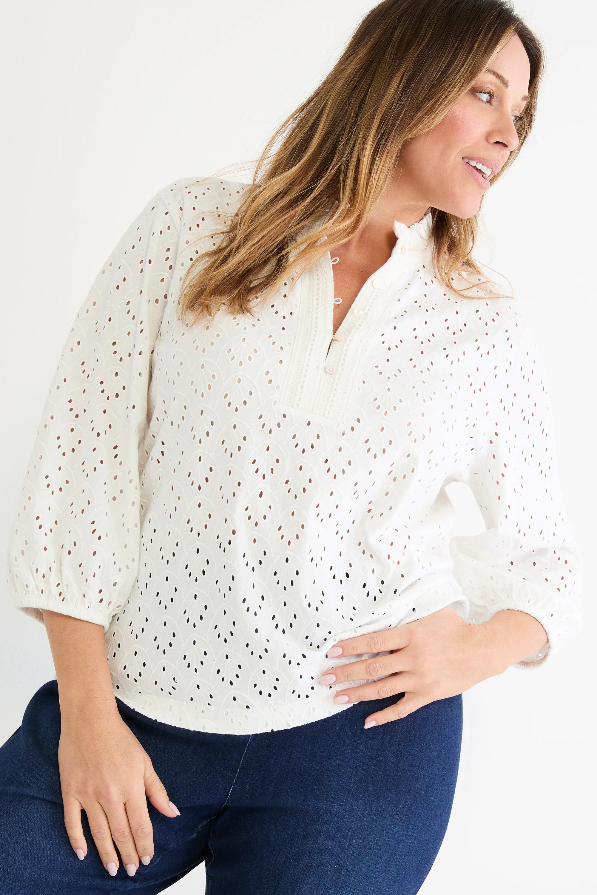 White knit eyelet top with a ruffle neck, front button closure, and 3/4 sleeves with elastic cuffs.