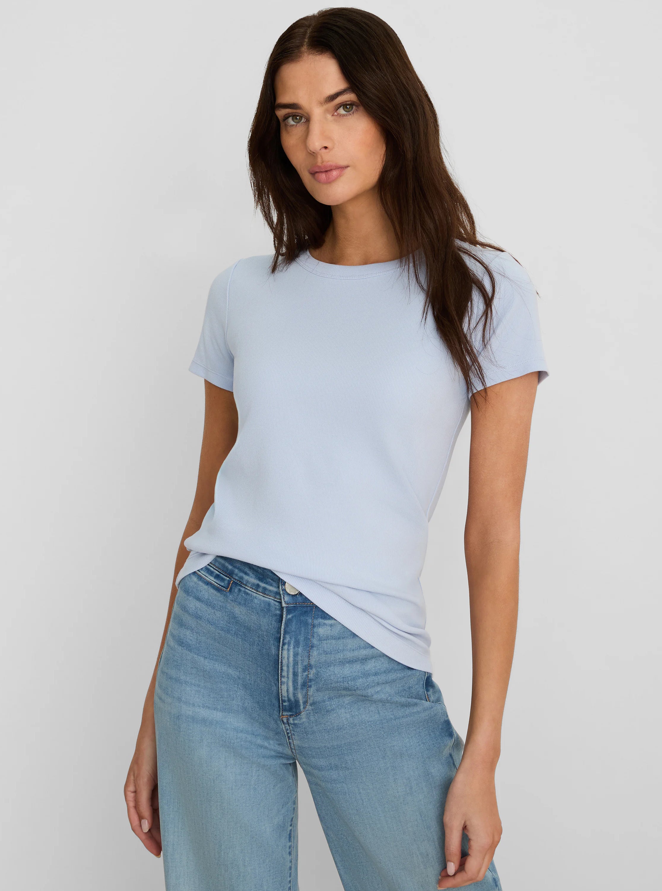 Light blue ribbed knit short sleeve crew neck tee, fitted on model. Paired with light wash jeans.