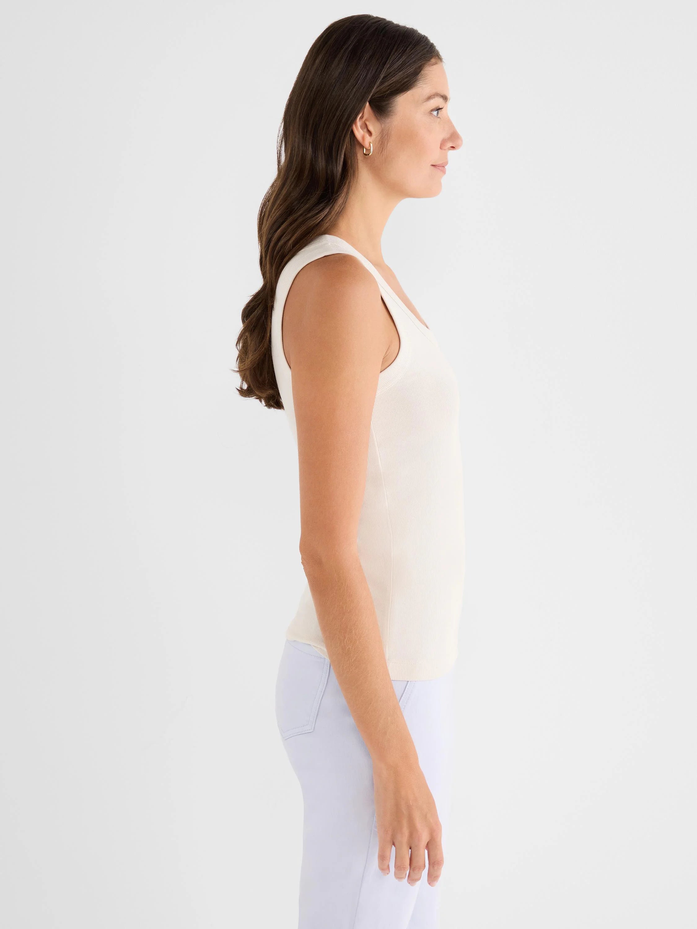 Woman in side profile wearing a cream, ribbed scoop tank.
