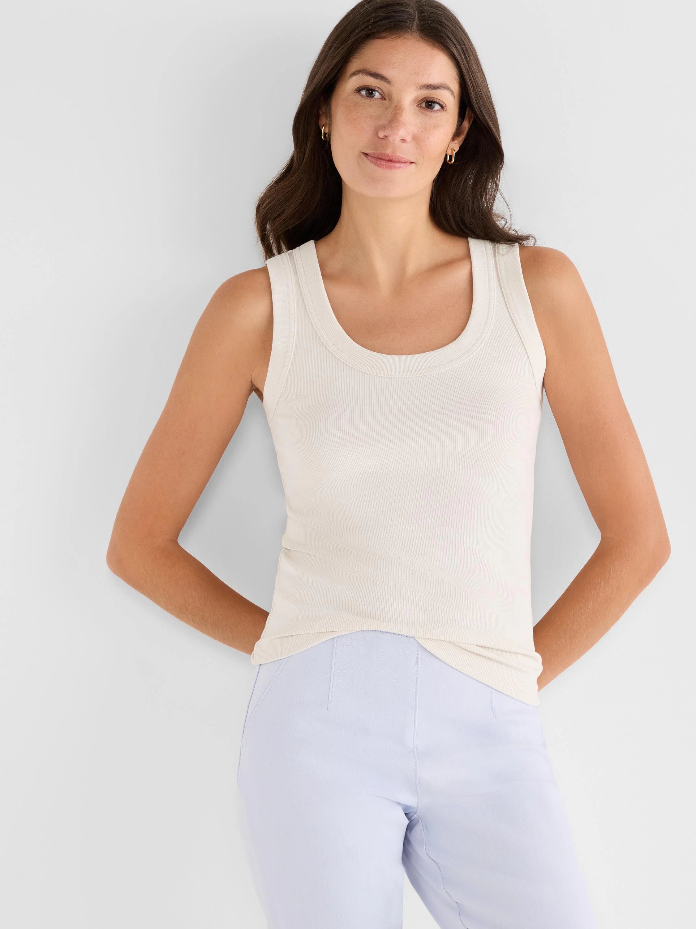 Off-white, finely ribbed scoop tank top, shown fitted on a model wearing light blue pants.