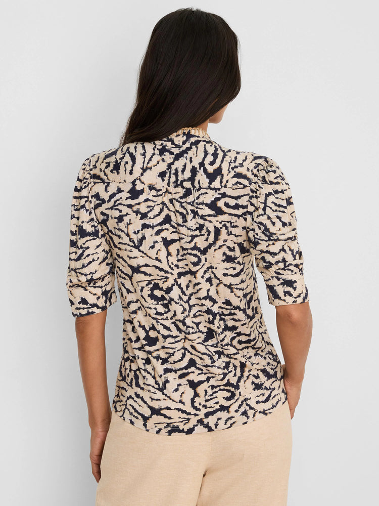 Tan and navy abstract swirl top with ruffled collar and puff sleeves.