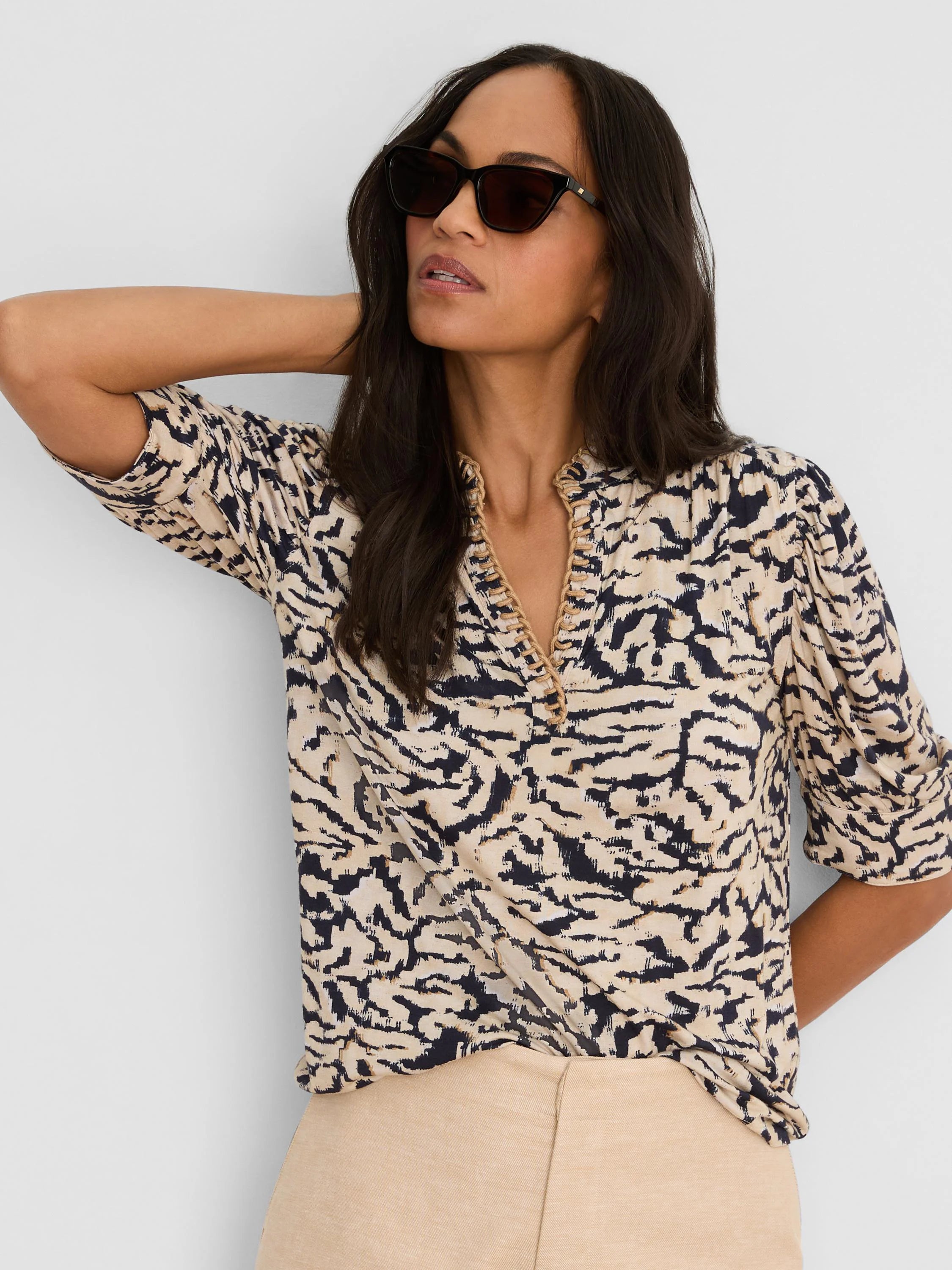 Beige top with dark blue irregular swirl pattern, braided V-neck, and three-quarter sleeves.