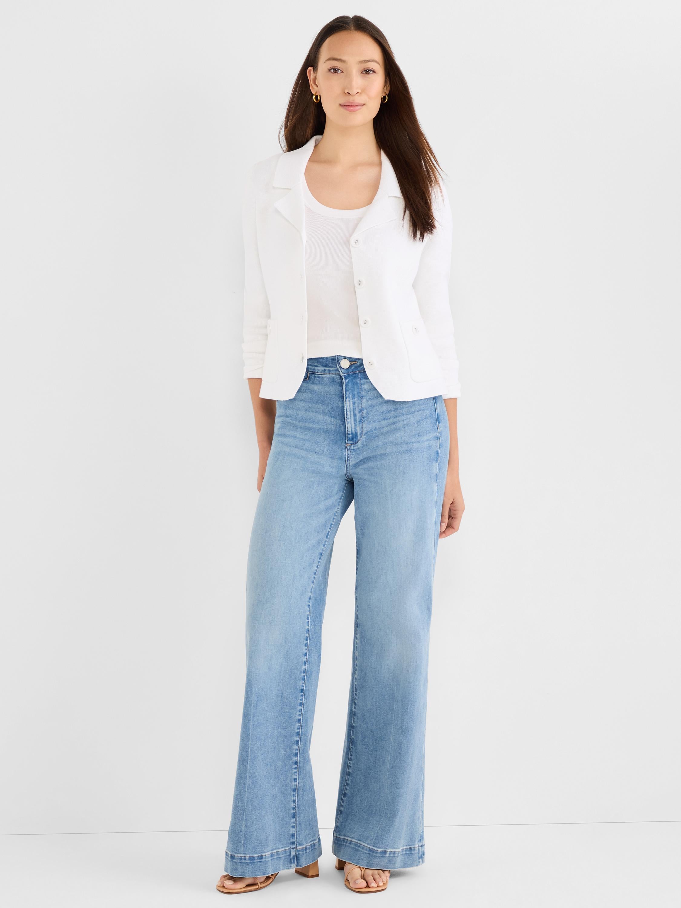 Model wears high-waisted, light wash, wide-leg denim jeans paired with a white knit cropped jacket.