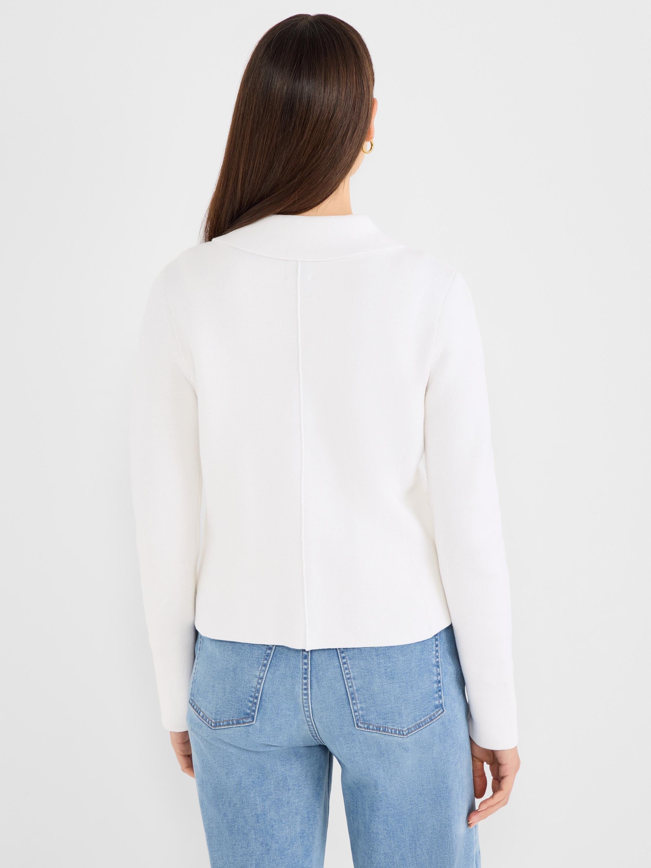 The model wears a fitted white knit sweater featuring a stand collar and a prominent vertical center back seam.