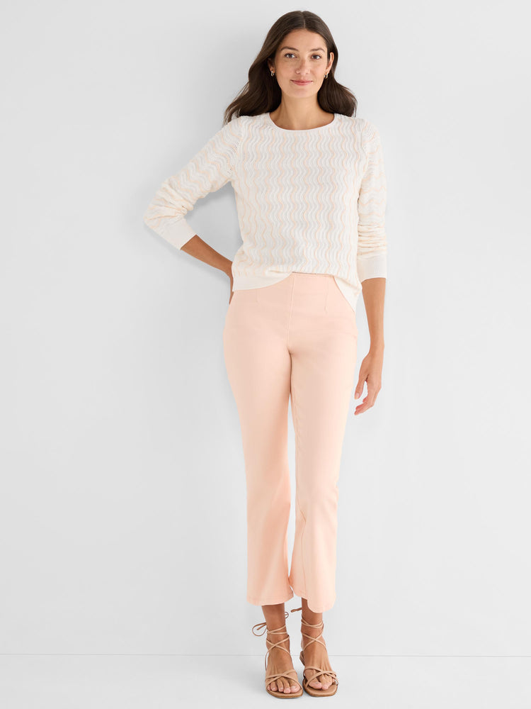 A model wears a white and peach wavy textured sweater with peach slim fit cropped flare pants and tan strappy sandals.
