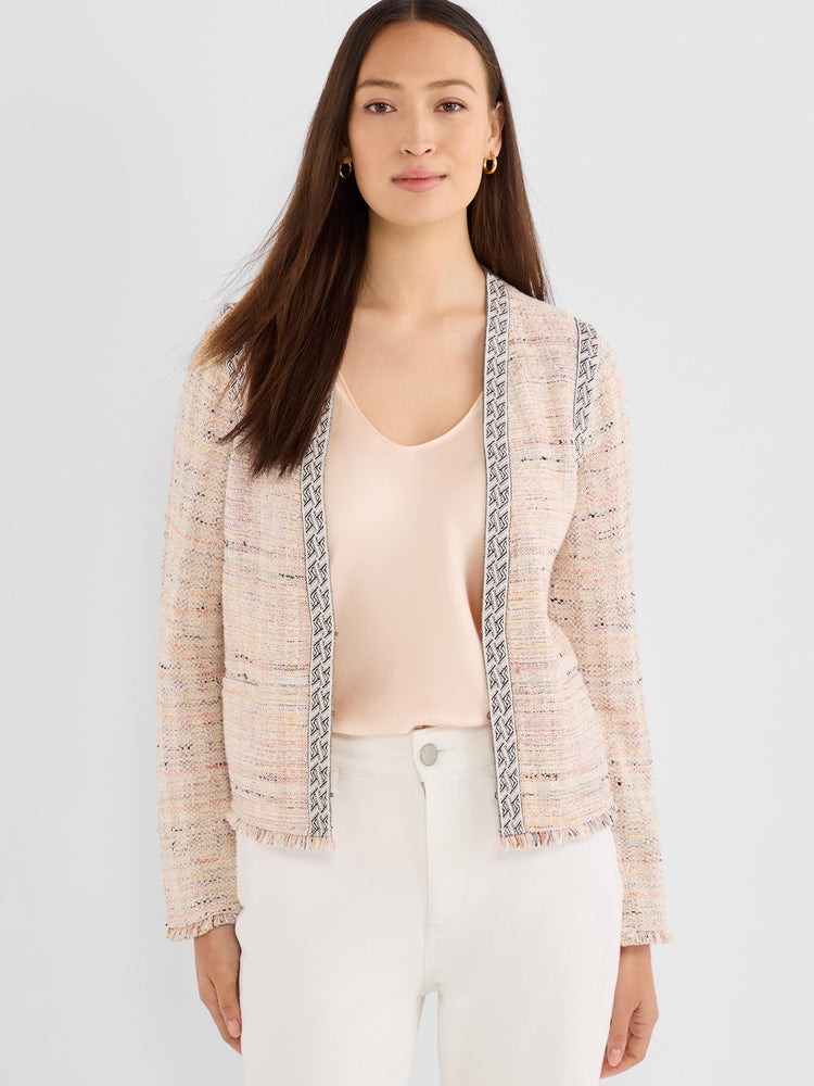 A model wears a light pink speckled tweed jacket featuring ornamental braided trim and a frayed hem.