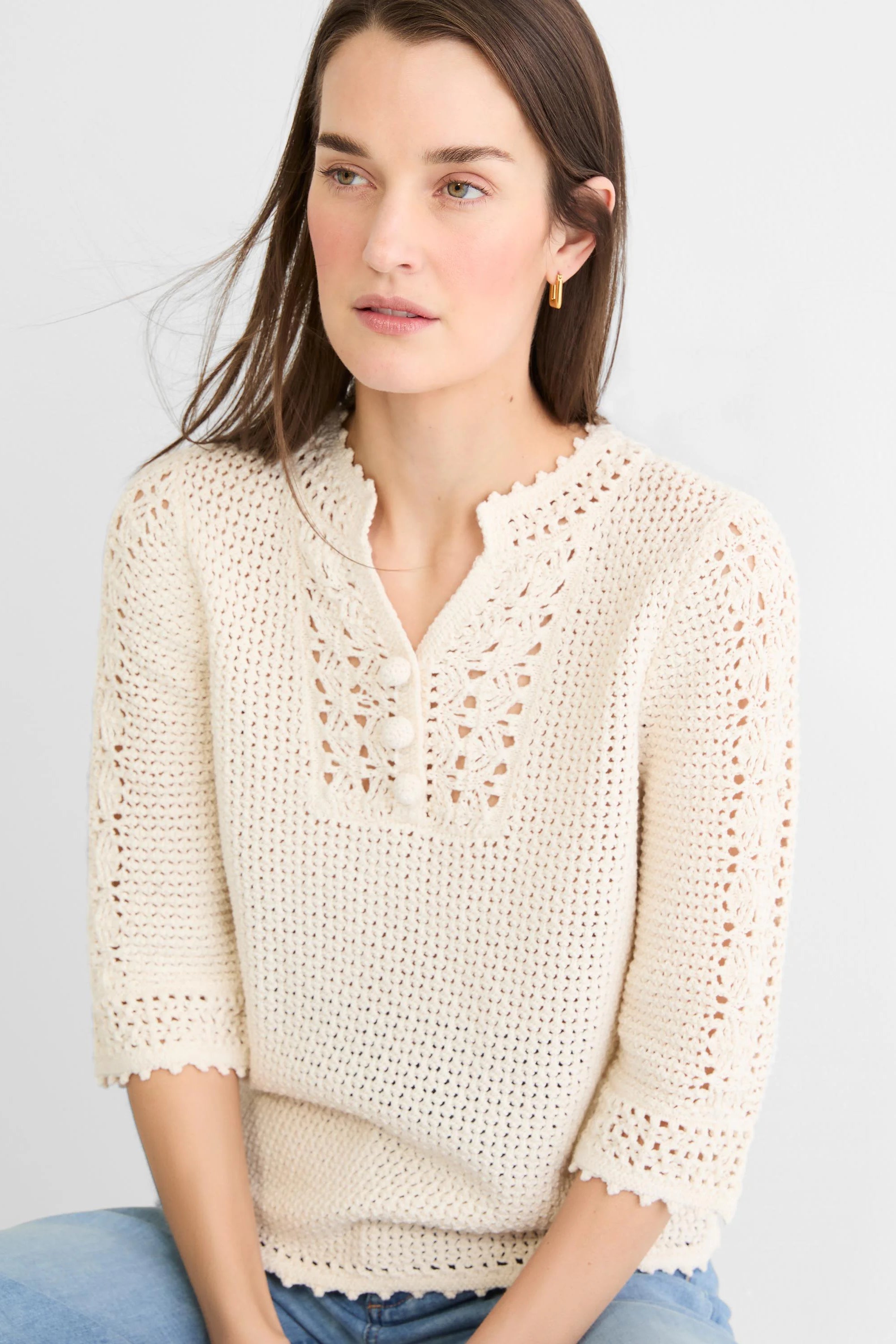 Cream crochet mesh sweater with openwork details at the V-neck, 3 buttons, and scalloped trim.