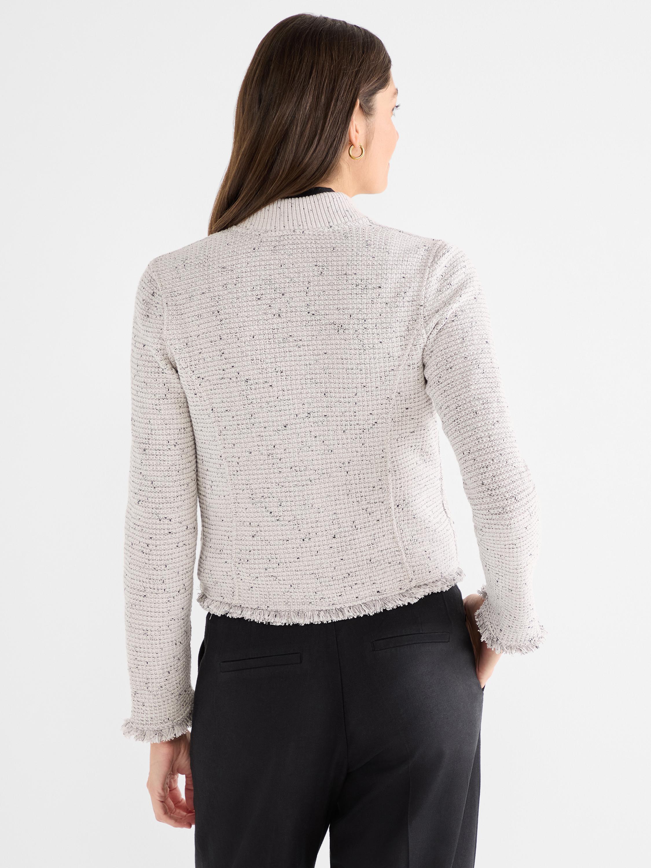 Model wears a fitted, cropped beige tweed jacket with a stand collar and textured fringe detail.