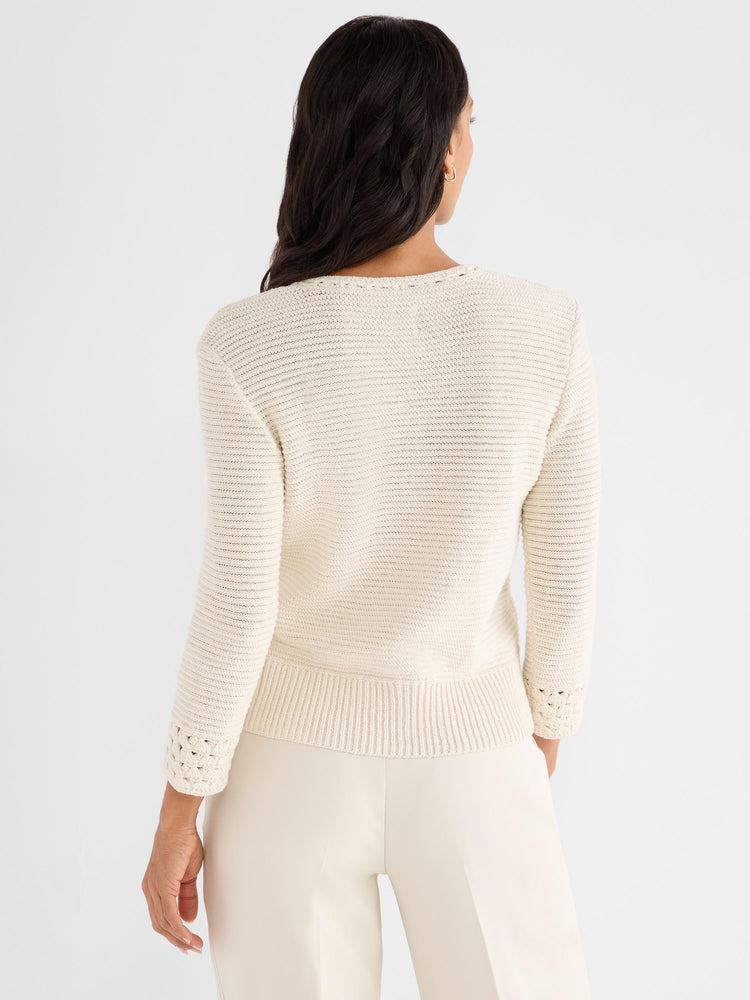 Fitted cream knit sweater features subtle textured stitching, a ribbed hem, and open crochet cuffs.