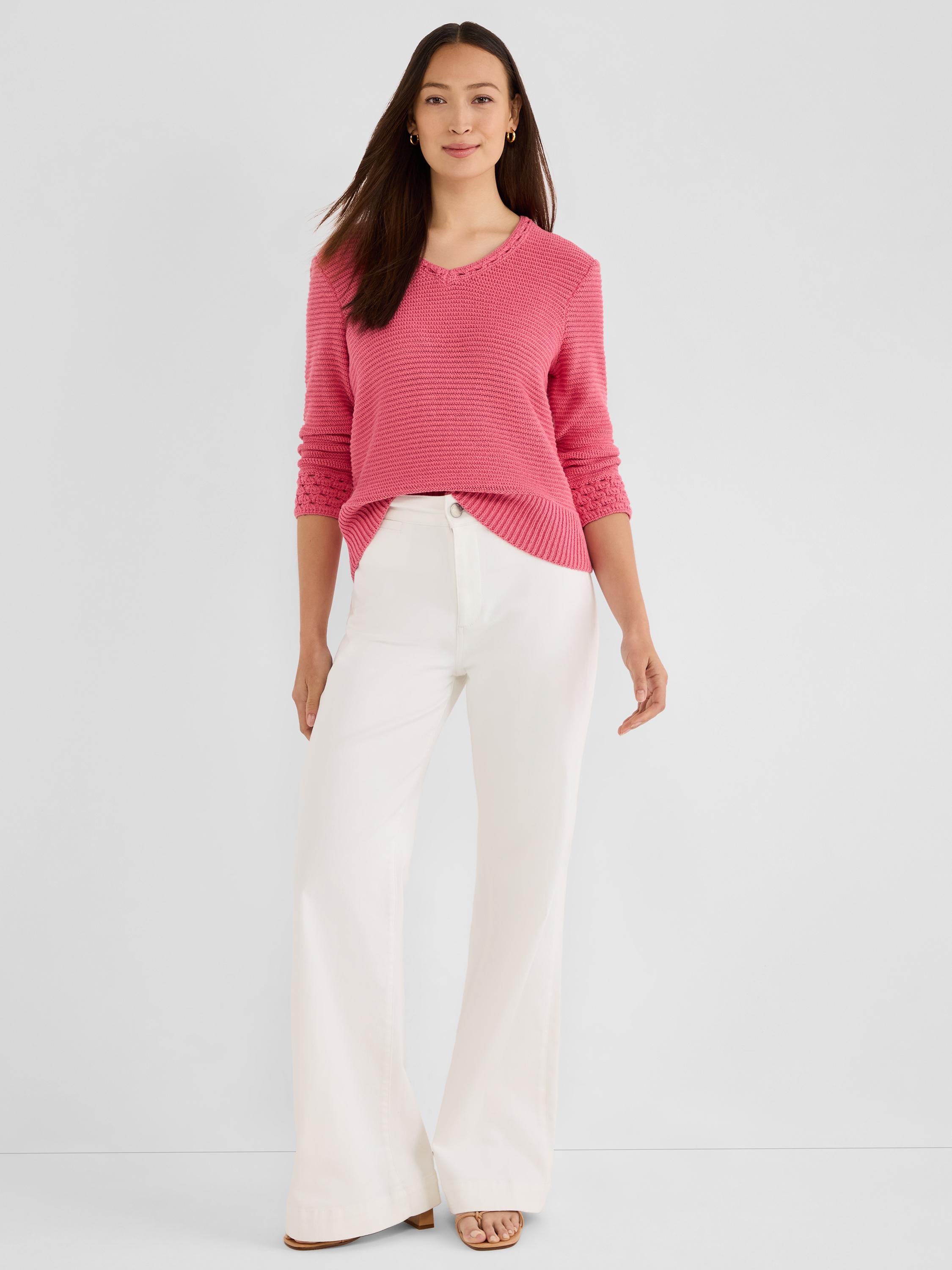 A relaxed fit, textured pink sweater with a crocheted V-neckline and three-quarter sleeves with decorative cuffs.