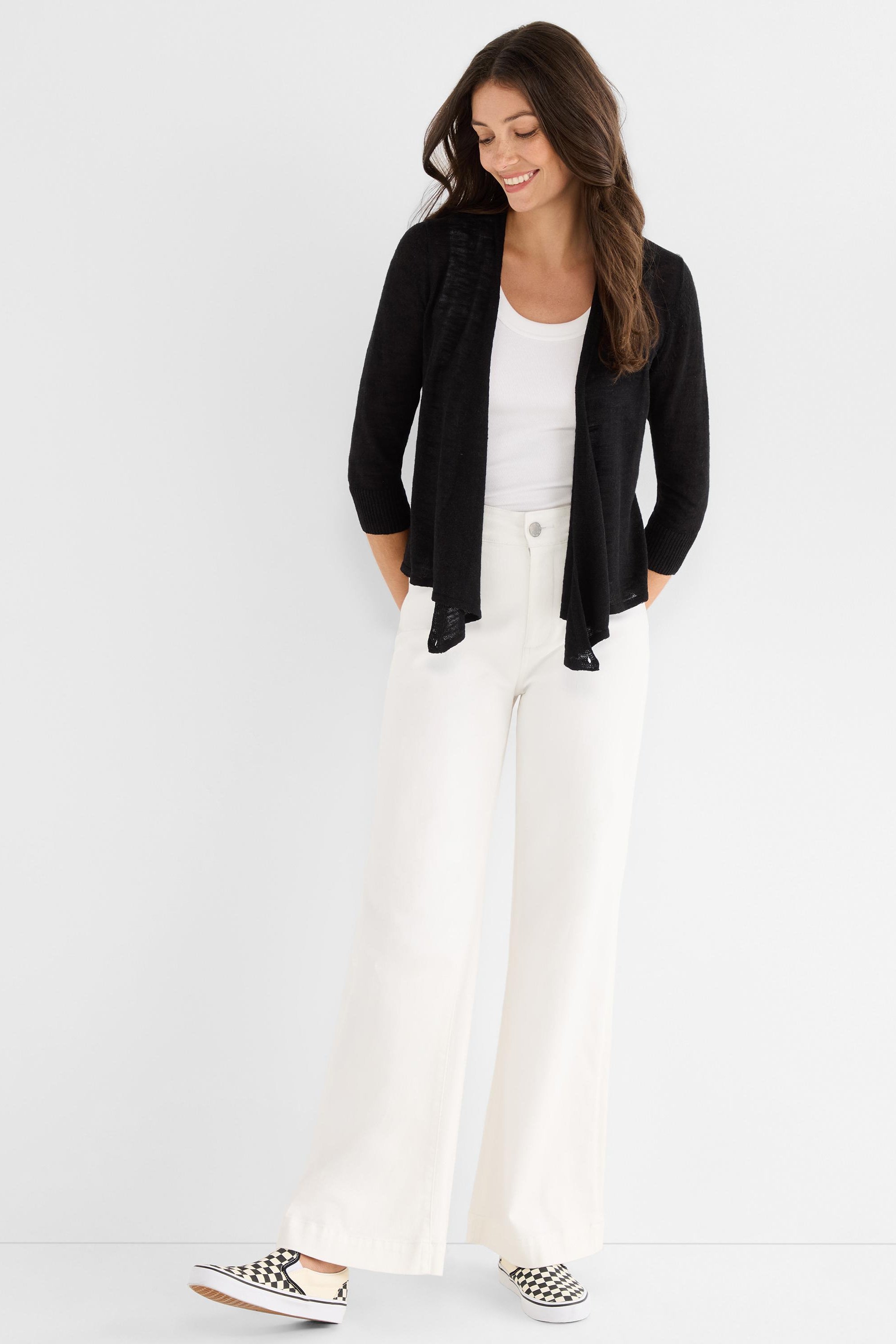 A sheer black knit open cardigan is worn, featuring a draped front and three-quarter length sleeves.