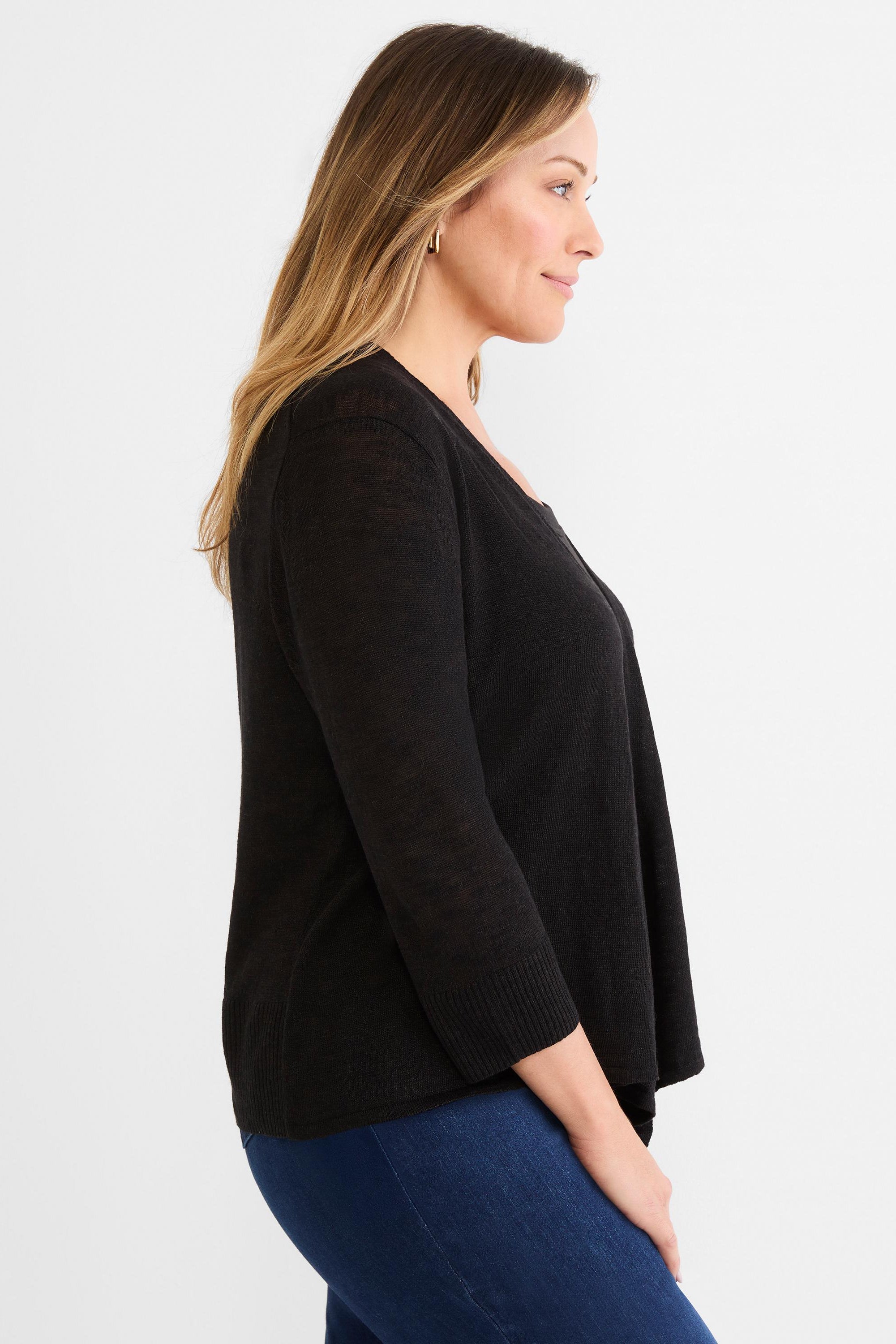 Black lightweight draped open cardigan with three-quarter sleeves, worn by a model over blue jeans.