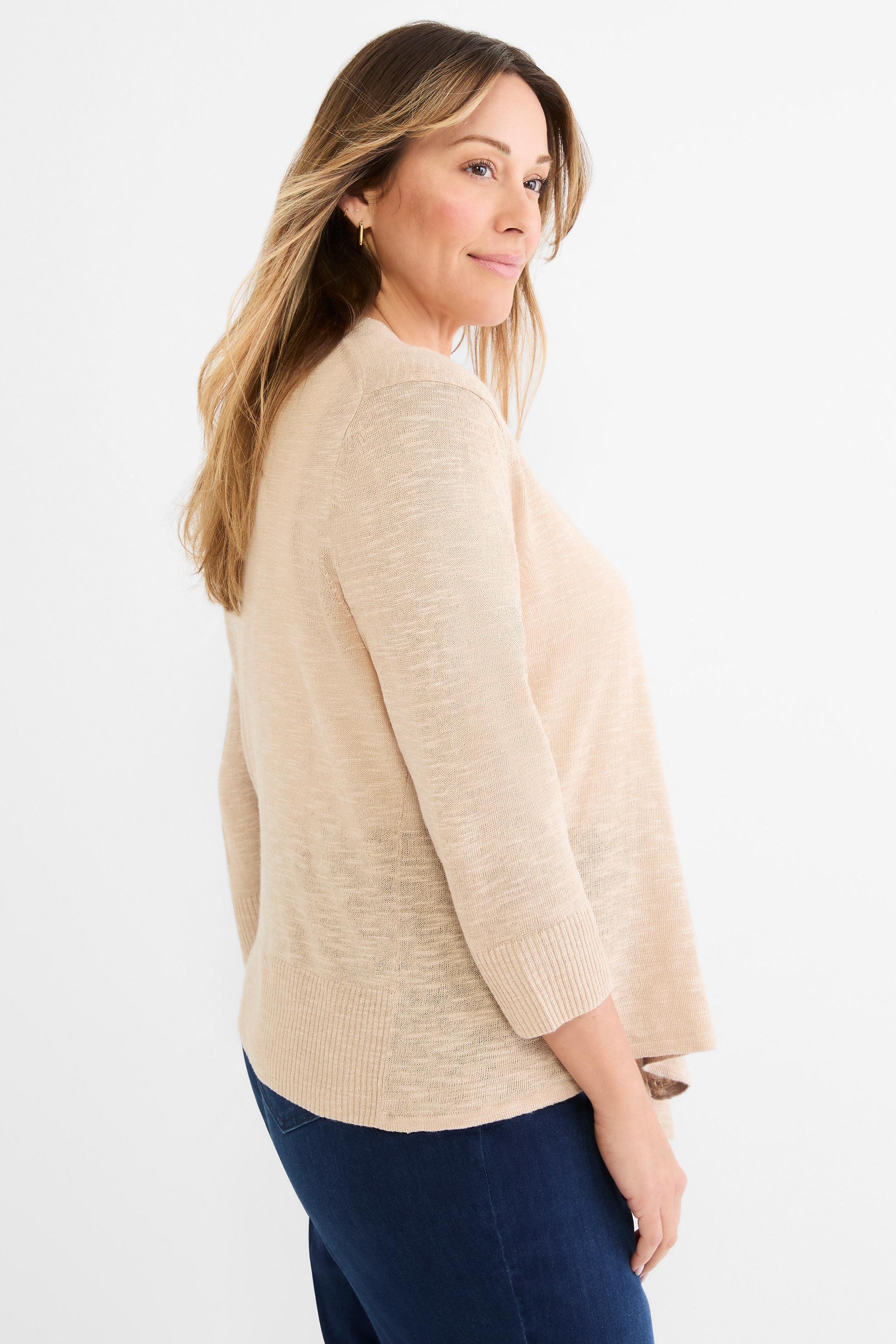 A model wears a relaxed fit beige fine knit open cardigan featuring 3/4 length sleeves and ribbed trim.