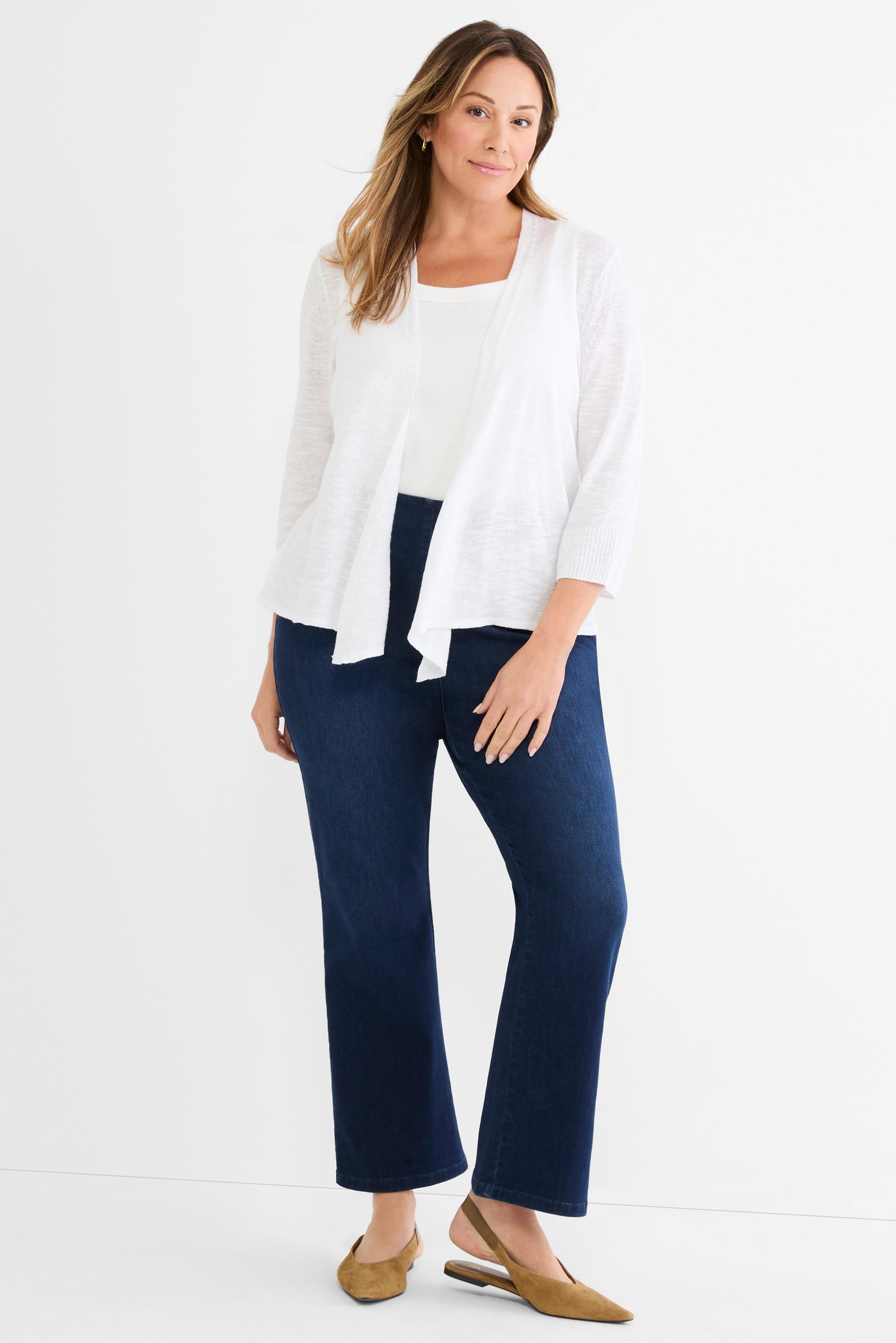 Model wears a lightweight white open-front cardigan with three-quarter sleeves and dark indigo straight-leg jeans.