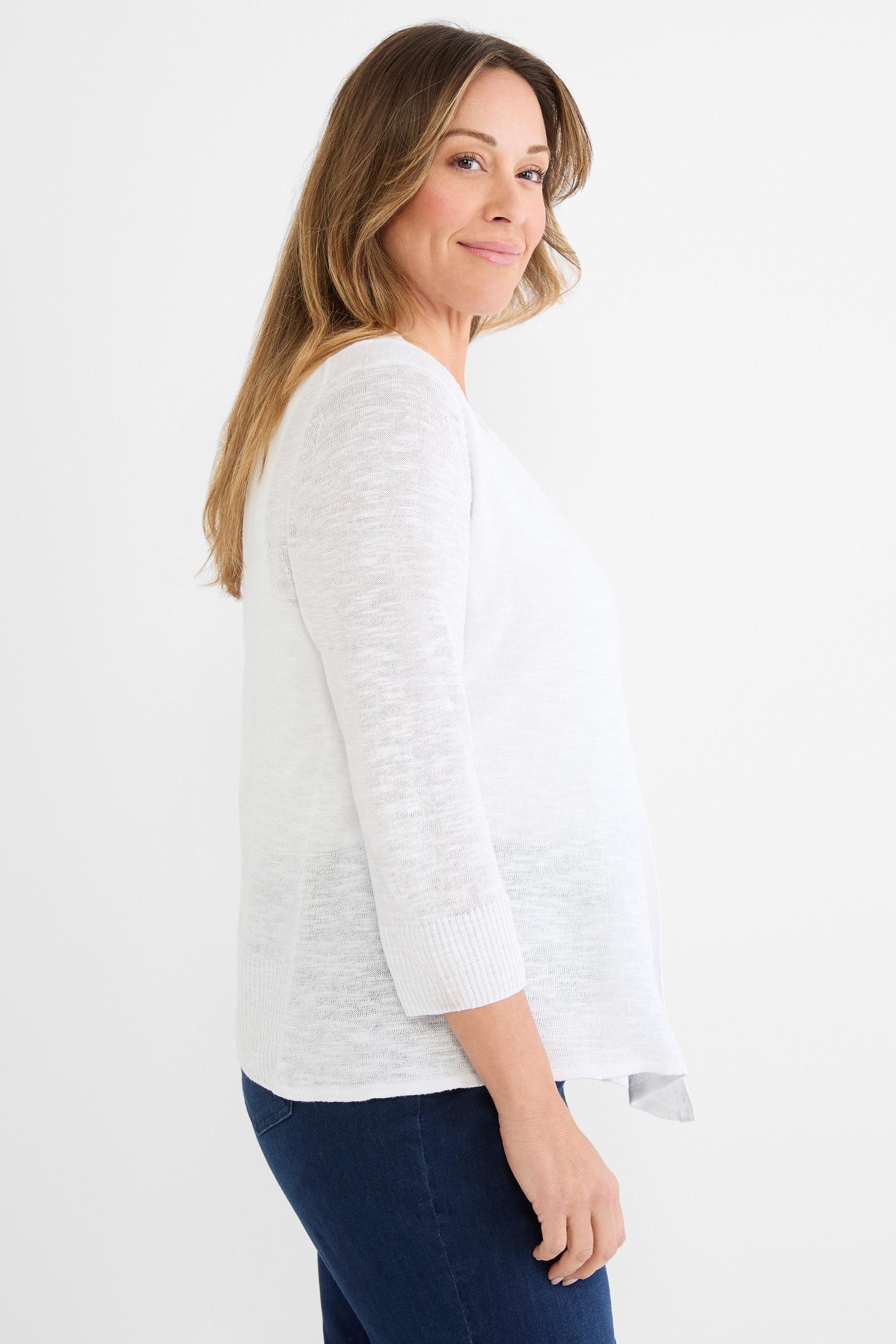 Model wears a white, lightweight knit cardigan with a flowy fit, three-quarter ribbed sleeves, and an open front.