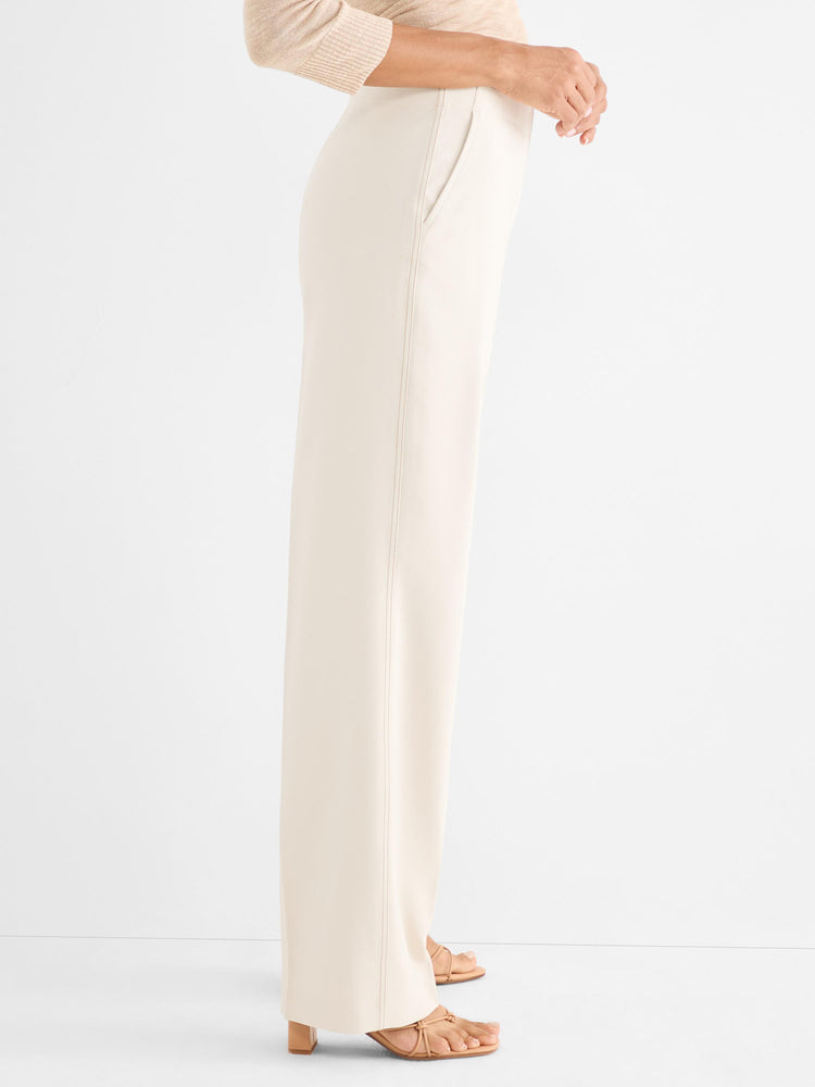 Cream wide-leg trousers with a high waist and stitched front seam detail are worn by the model.