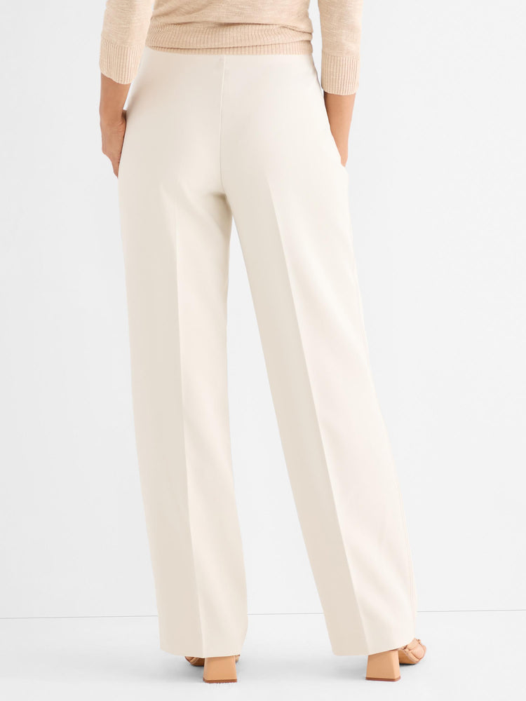 Elegant cream wide-leg trousers are styled high-waisted, showcasing a long, fluid drape and sharp pressed creases.