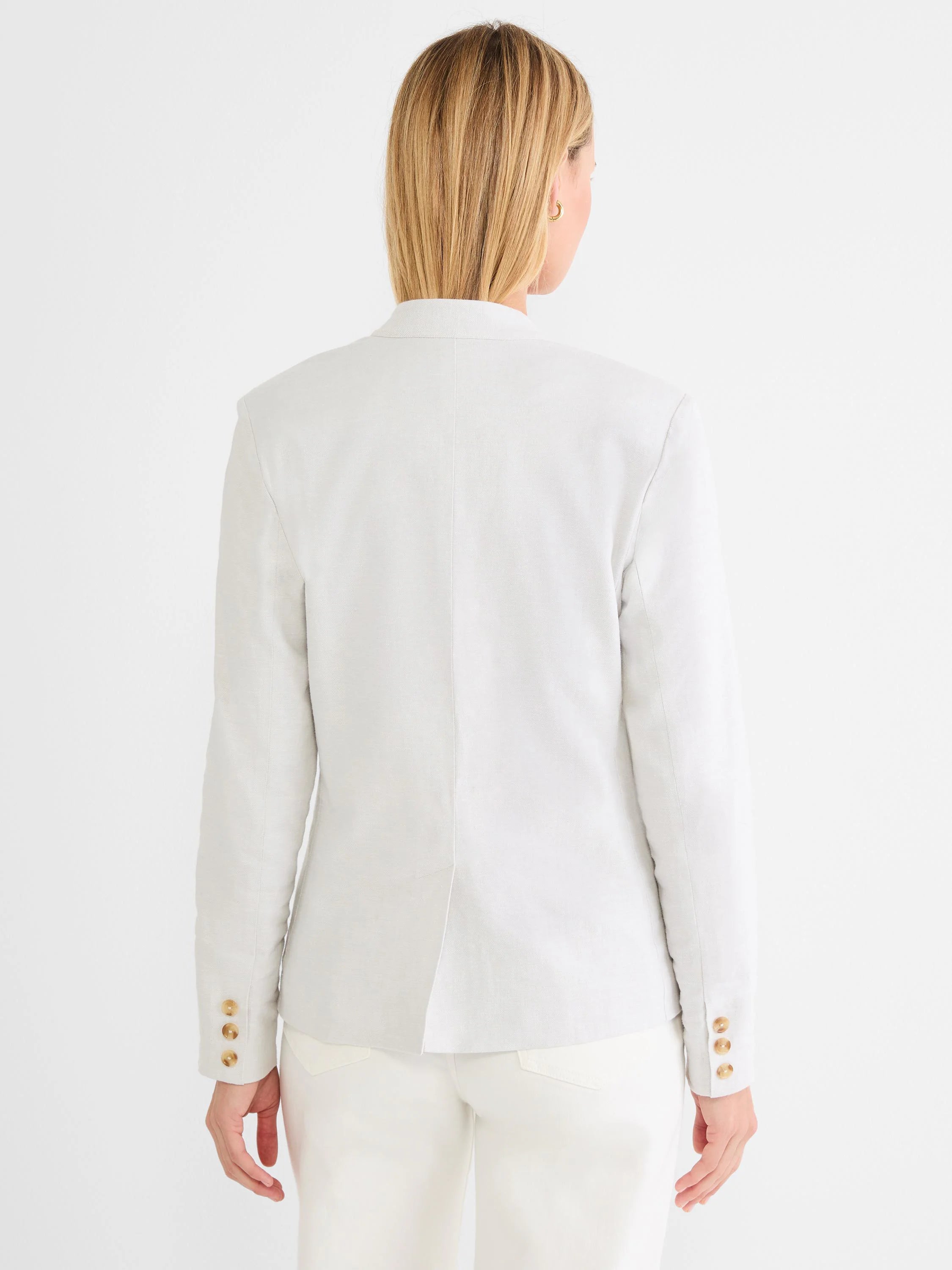 Back view of an oatmeal linen blazer with three brown cuff buttons and a center back vent.