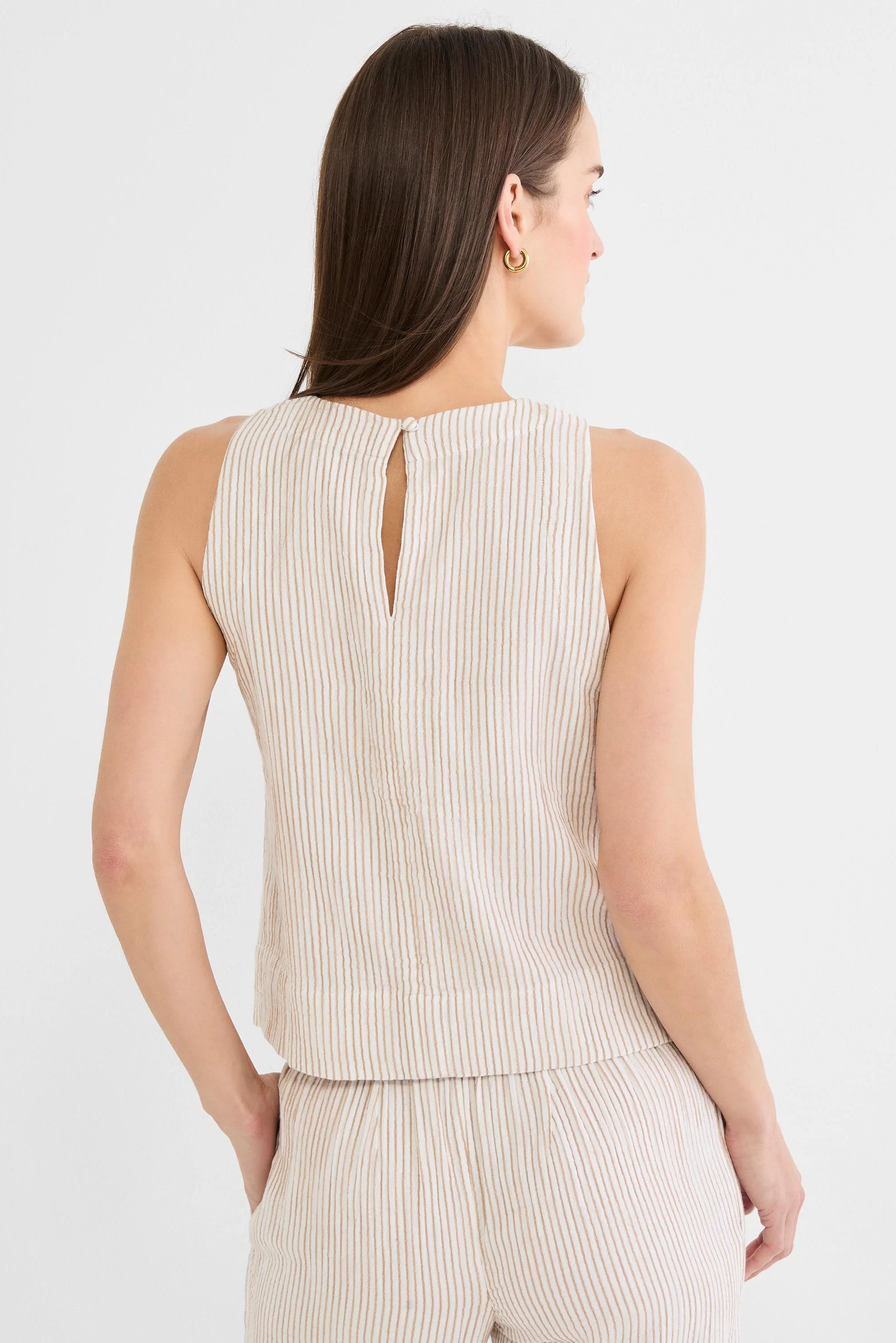 Back view of a cream sleeveless tank top with vertical brown pinstripes. Features a keyhole opening and button closure at...